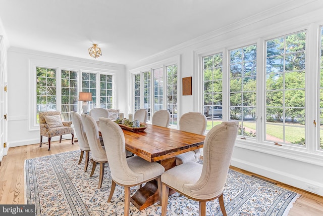 dining space featuring light hardwood / wood-style flooring, crown molding, and a wealth of natural light