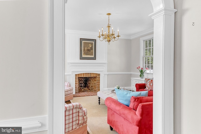 sitting room featuring a fireplace, crown molding, carpet, decorative columns, and a chandelier