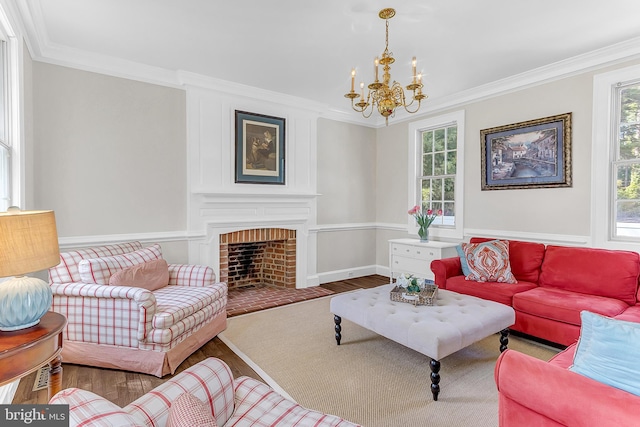 living room with a brick fireplace, an inviting chandelier, crown molding, and hardwood / wood-style flooring