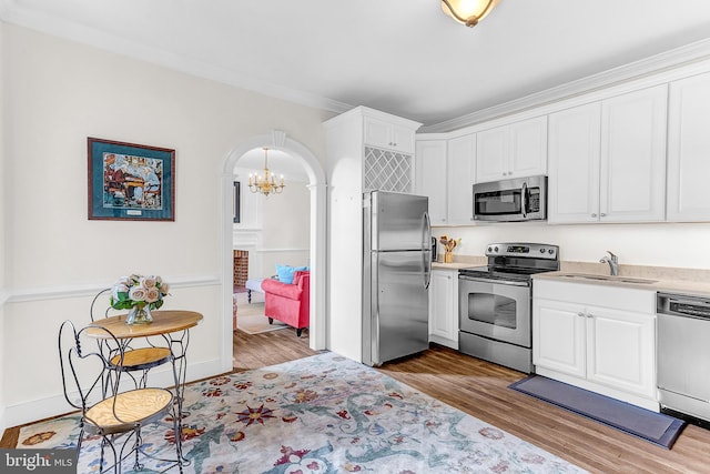 kitchen with stainless steel appliances, white cabinetry, light wood-type flooring, and sink