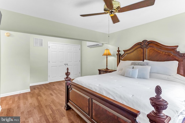 bedroom with an AC wall unit, a closet, light hardwood / wood-style floors, and ceiling fan