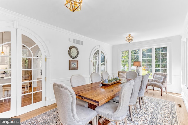 dining room featuring light wood-type flooring, french doors, and crown molding