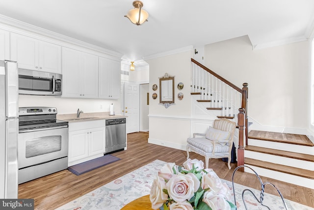 kitchen with light hardwood / wood-style flooring, white cabinetry, appliances with stainless steel finishes, and sink