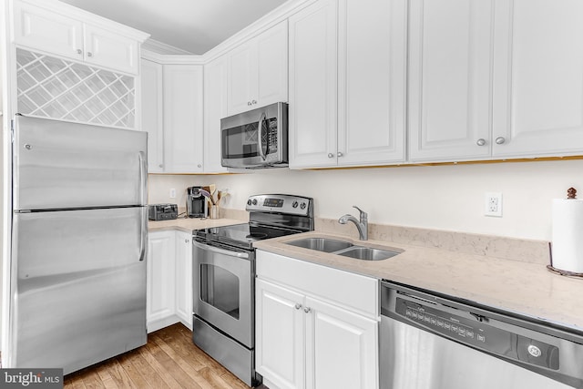 kitchen featuring white cabinets, appliances with stainless steel finishes, light wood-type flooring, and sink