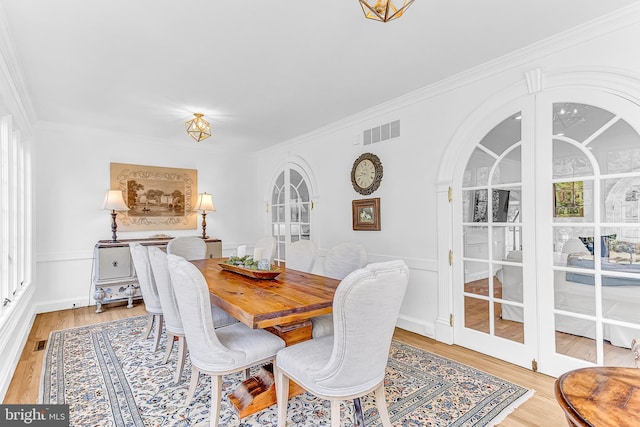 dining area with french doors, ornamental molding, plenty of natural light, and light hardwood / wood-style floors