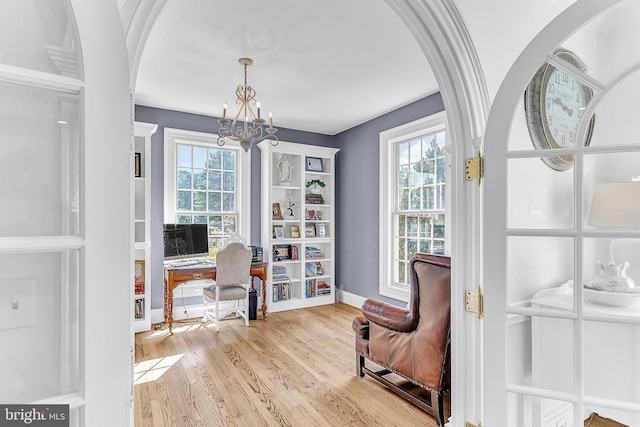 living area with a chandelier, light hardwood / wood-style floors, and a healthy amount of sunlight