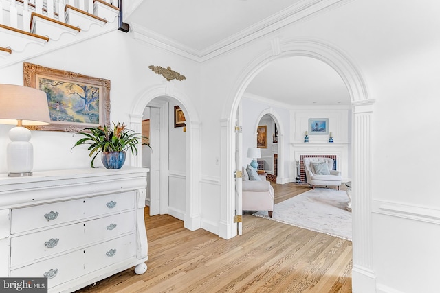 hall with light hardwood / wood-style floors and ornamental molding