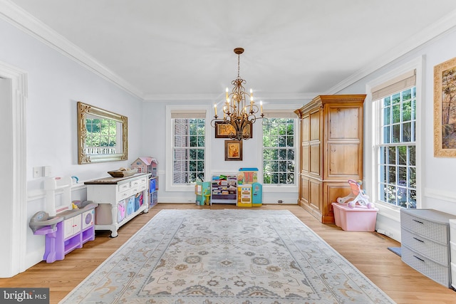 living area with an inviting chandelier, light wood-type flooring, and crown molding