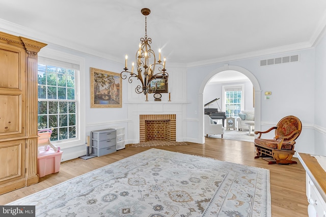 sitting room with light wood-type flooring, ornamental molding, and a brick fireplace