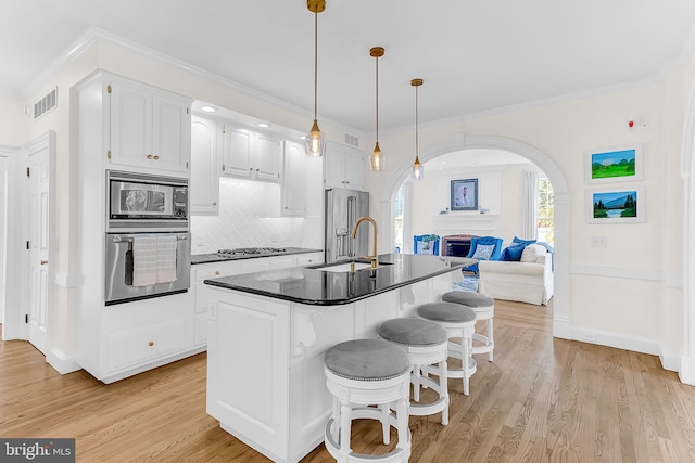 kitchen with pendant lighting, light wood-type flooring, sink, white cabinetry, and stainless steel appliances