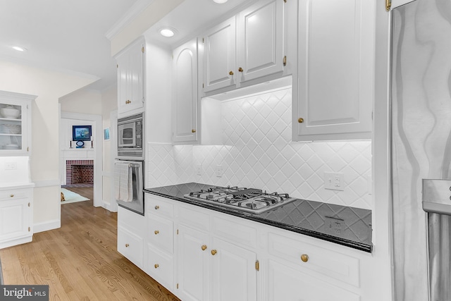 kitchen featuring backsplash, white cabinetry, light hardwood / wood-style flooring, and stainless steel appliances