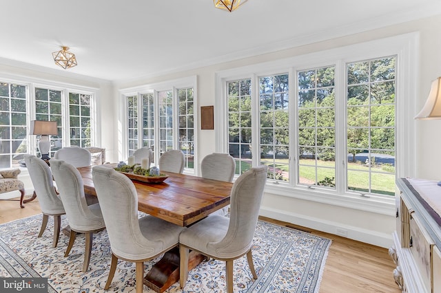 dining area with crown molding and light hardwood / wood-style floors