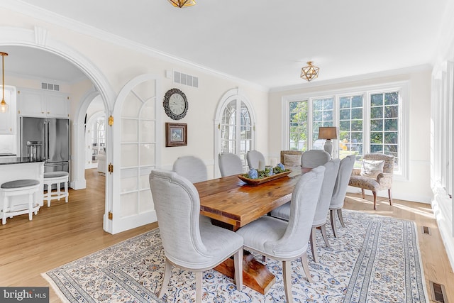 dining space featuring light wood-type flooring and ornamental molding