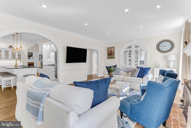 living room featuring crown molding, light hardwood / wood-style floors, sink, and a chandelier