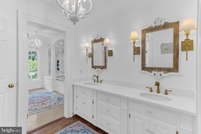 bathroom with an inviting chandelier, ornamental molding, hardwood / wood-style floors, and vanity