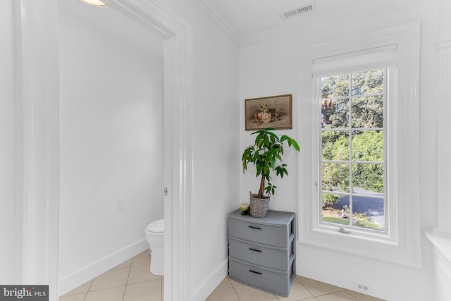 bathroom with tile patterned floors, crown molding, a healthy amount of sunlight, and toilet