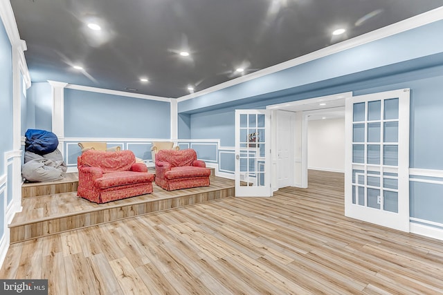 living room featuring light wood-type flooring, french doors, and crown molding