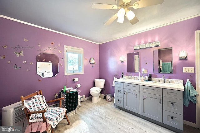 bathroom with toilet, ornamental molding, vanity, wood-type flooring, and ceiling fan