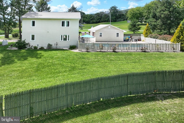 rear view of property featuring a patio, a yard, and a swimming pool side deck