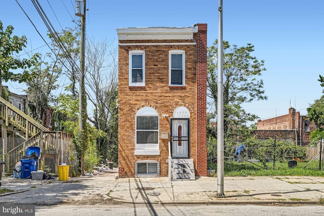 view of front of house featuring central air condition unit, fence, and brick siding