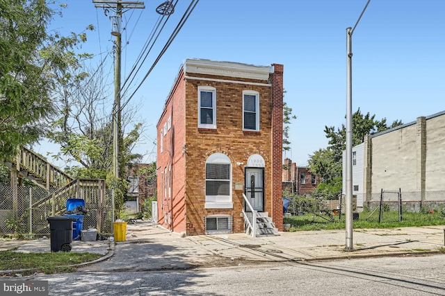 townhome / multi-family property with entry steps, brick siding, a chimney, and fence