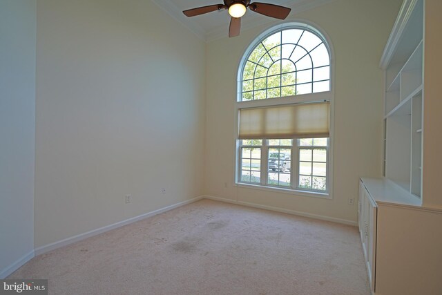 carpeted spare room featuring crown molding, a towering ceiling, and ceiling fan