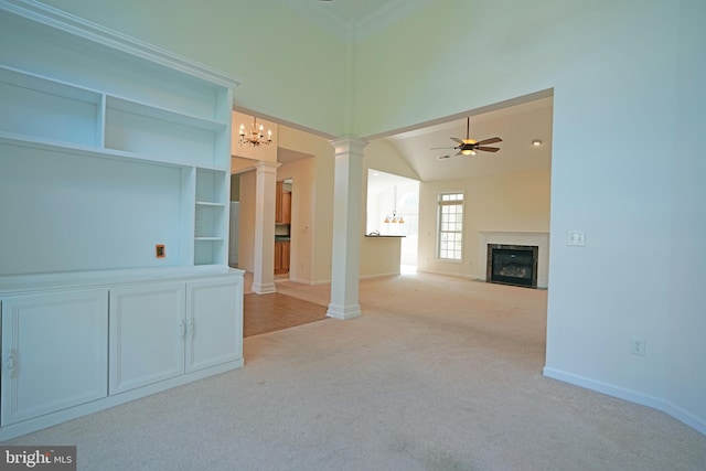 unfurnished living room with a premium fireplace, ceiling fan with notable chandelier, light carpet, and decorative columns