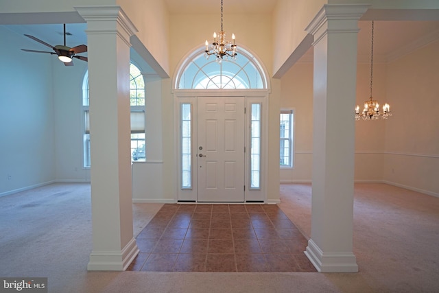 foyer entrance with ceiling fan with notable chandelier, carpet flooring, and ornate columns