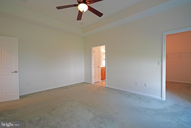 unfurnished bedroom featuring ensuite bathroom, light carpet, a closet, a spacious closet, and ceiling fan