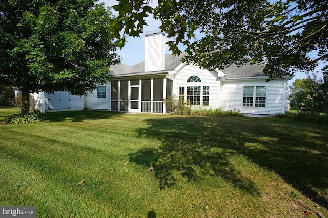 rear view of property featuring a lawn and a sunroom