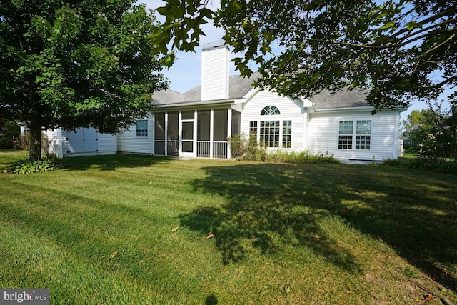 back of house with a sunroom, a yard, and a chimney