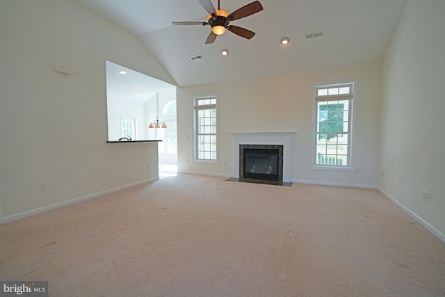 unfurnished living room featuring plenty of natural light, ceiling fan, a high end fireplace, and light colored carpet