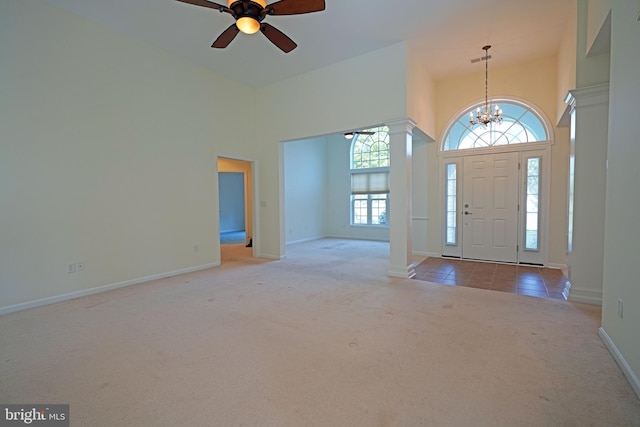 carpeted foyer featuring ceiling fan with notable chandelier and a towering ceiling