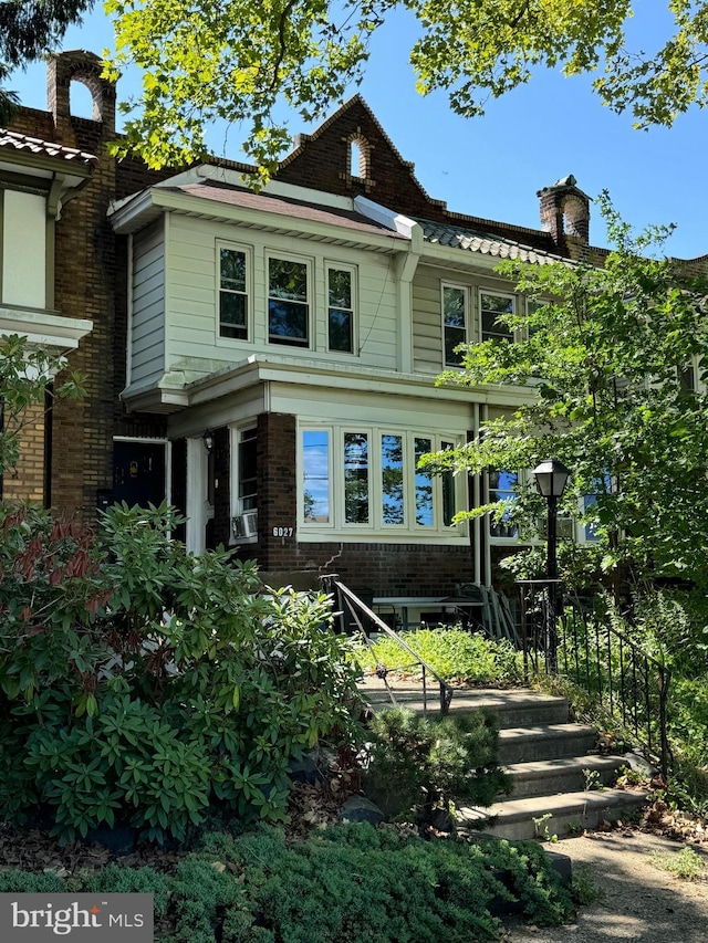 view of front of property with a chimney and brick siding