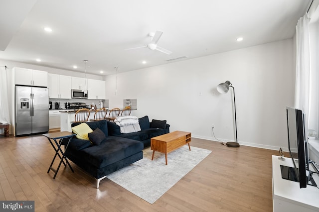 living room with light hardwood / wood-style flooring and ceiling fan