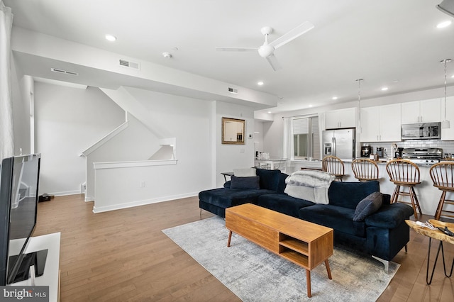 living room with ceiling fan and light wood-type flooring