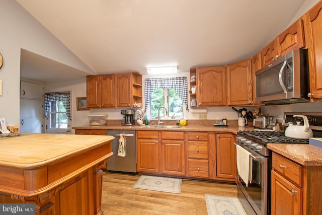 kitchen featuring light wood-type flooring, appliances with stainless steel finishes, sink, and lofted ceiling