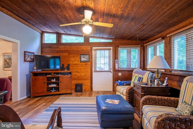 living room with light hardwood / wood-style floors, wood walls, ceiling fan, and lofted ceiling