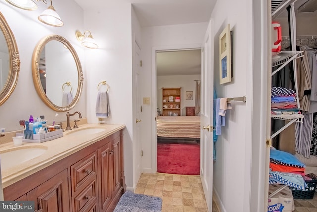 ensuite bathroom with connected bathroom, a walk in closet, a sink, and double vanity