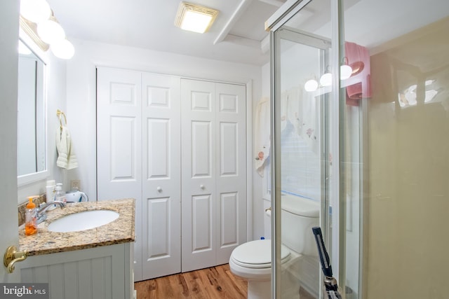 bathroom with toilet, walk in shower, vanity, and wood-type flooring