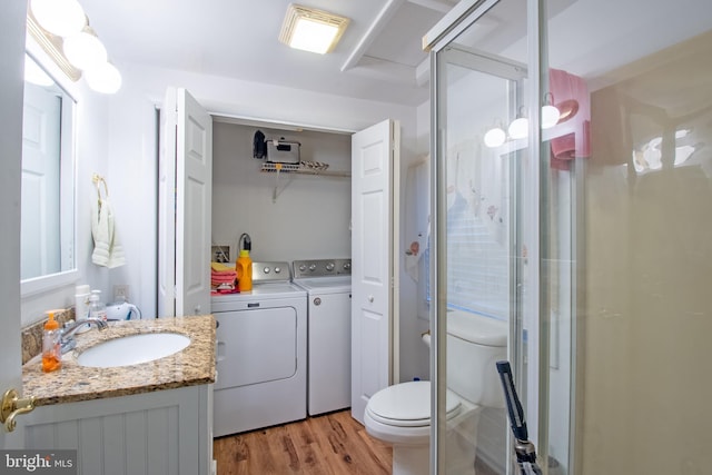 bathroom featuring toilet, a stall shower, vanity, wood finished floors, and independent washer and dryer