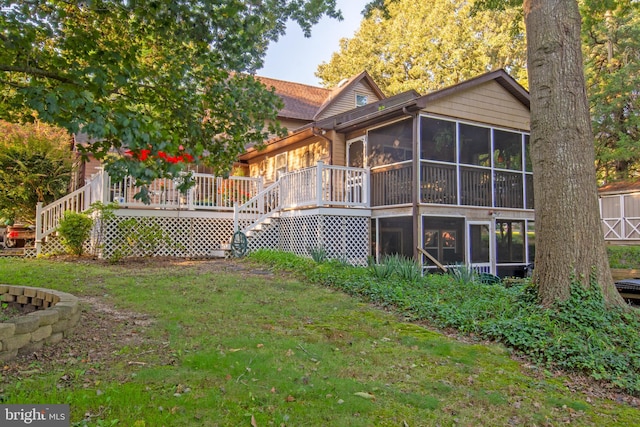 back of house featuring a lawn, a wooden deck, and a sunroom