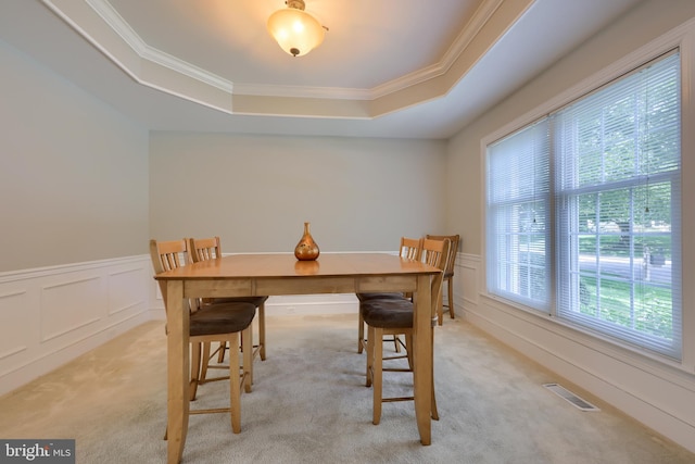 dining room with a raised ceiling, light carpet, and ornamental molding