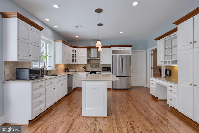 kitchen with a center island, decorative light fixtures, appliances with stainless steel finishes, white cabinetry, and sink