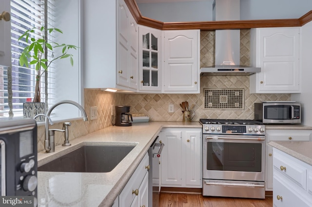 kitchen featuring white cabinets, appliances with stainless steel finishes, plenty of natural light, sink, and wall chimney exhaust hood