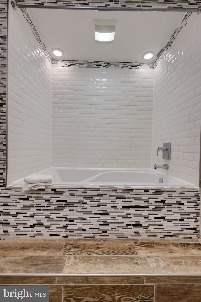 bathroom with tiled tub and hardwood / wood-style flooring