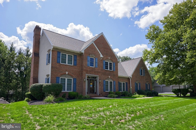 colonial house featuring a front yard and a garage