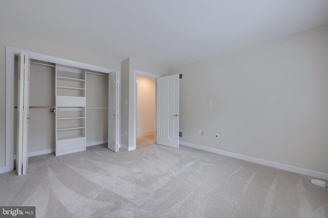 unfurnished bedroom featuring light colored carpet and a closet