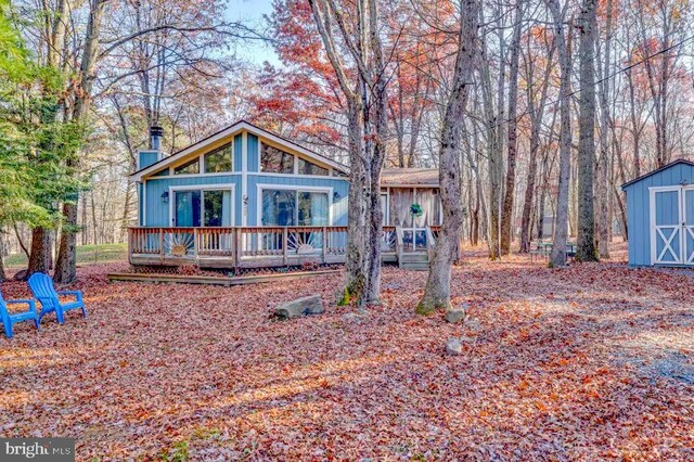 rear view of property with a storage shed and a wooden deck