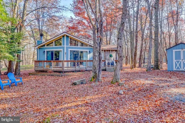 chalet / cabin featuring an outbuilding, a wooden deck, and a shed